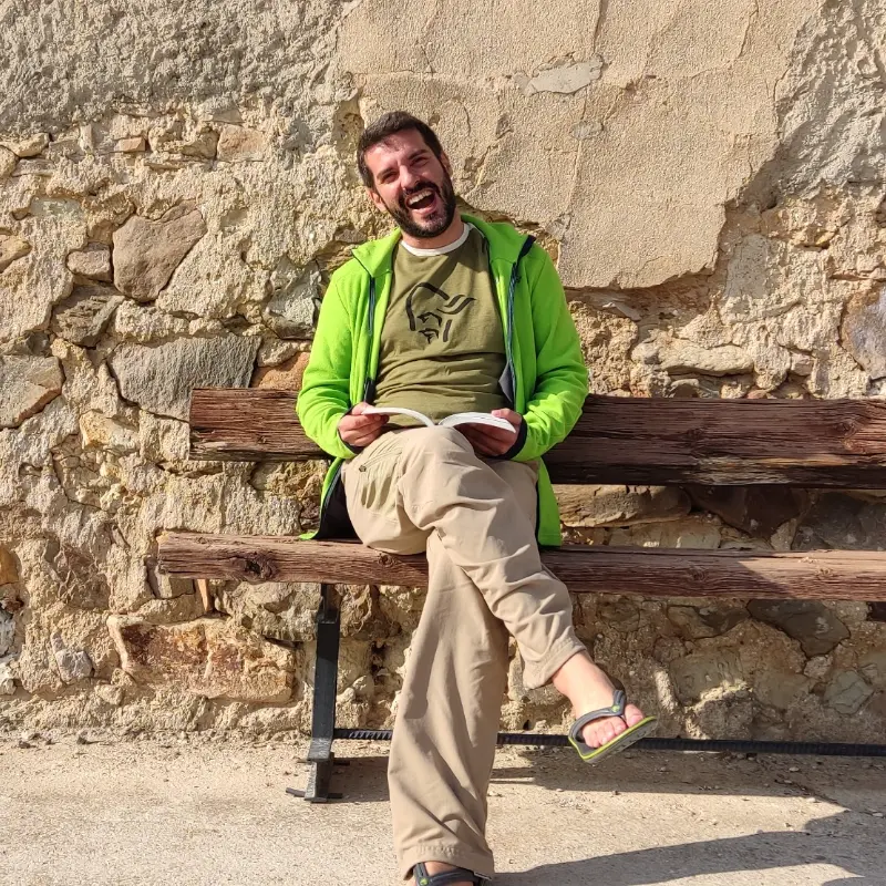 Foto a participante sonriente en un banco leyendo